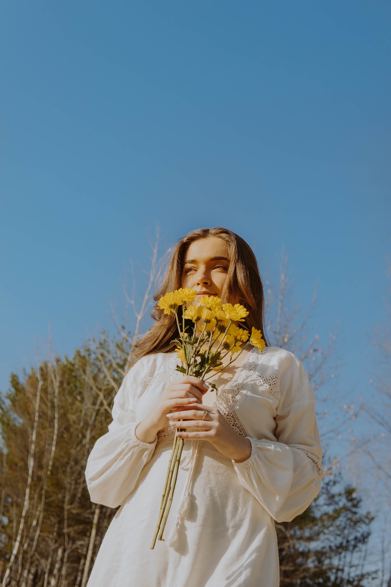 Woman in White Long Sleeve Dress Holding Bouquet of Flowers